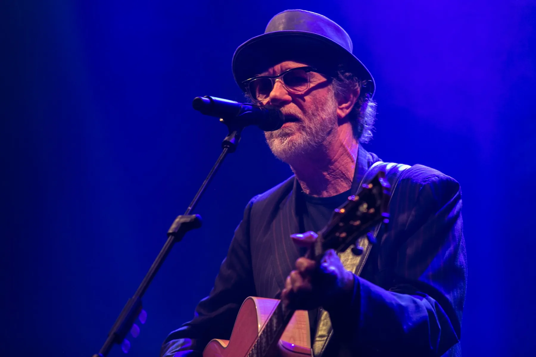 Cantautore con chitarra al microfono in luce blu