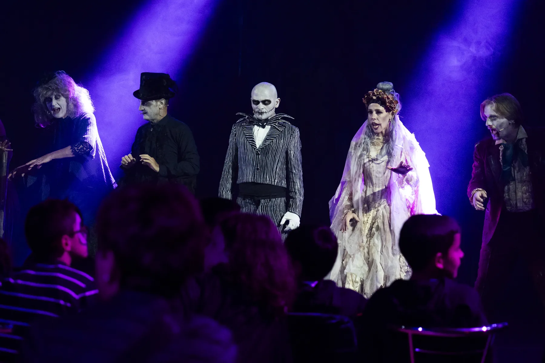 Attori in costume sul palco illuminato di viola