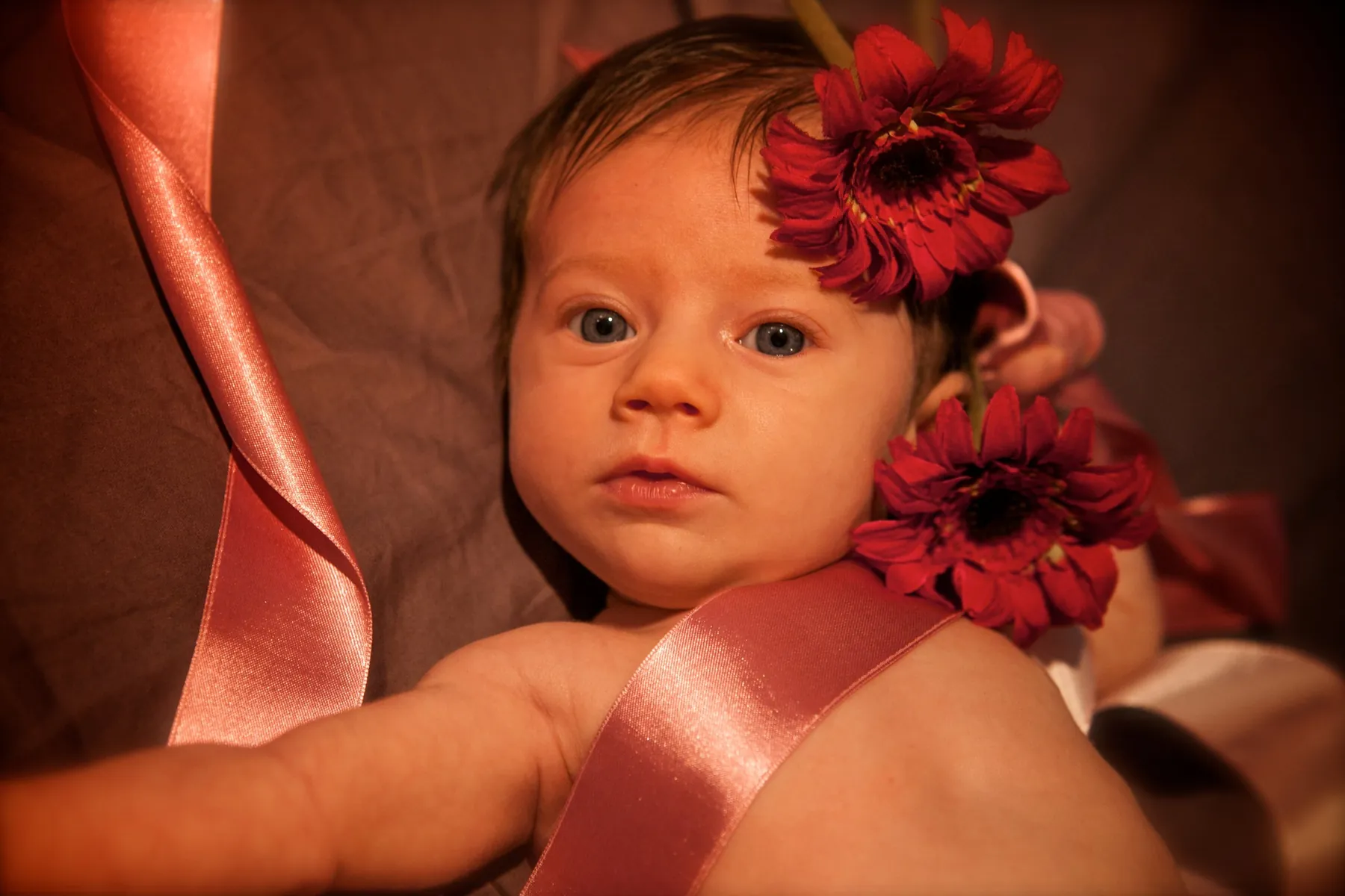 Neonata con fiori rossi e nastro rosa